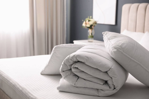 Pillows on a bed with a doona cover rolled up.